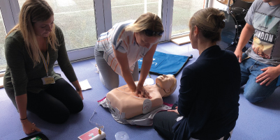 people performing CPR on dummy