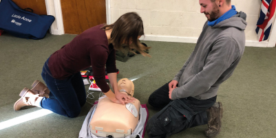 two people learning CPR on dummy